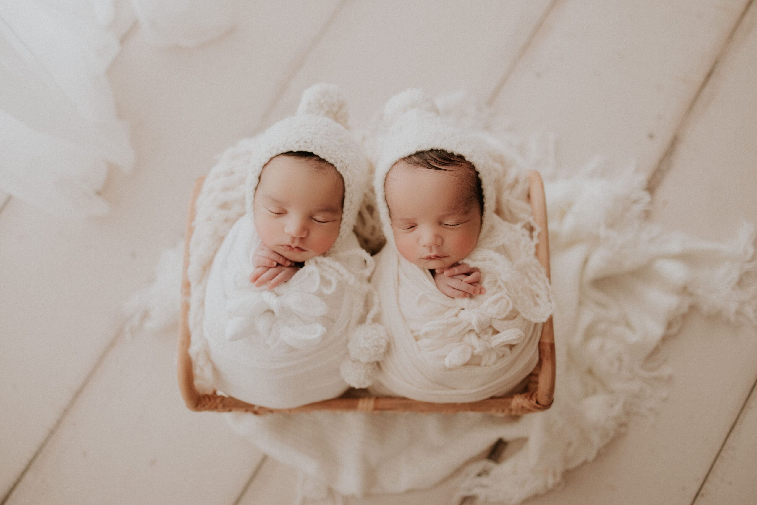 Twin newborn babies sleeping together in a soft neutral studio setup in Sacramento