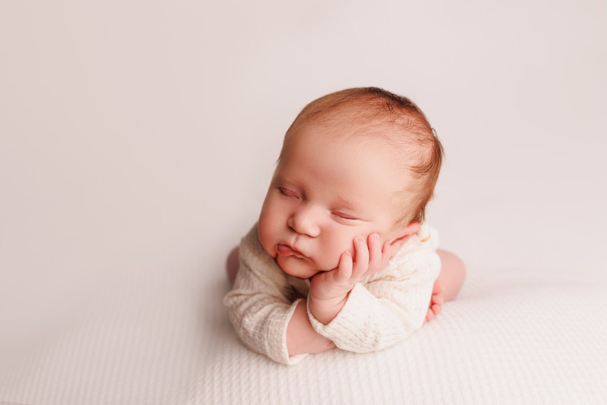 Timeless newborn portrait in Sacramento studio with creamy white and beige textures highlighting a sleeping baby in a natural, minimalist style