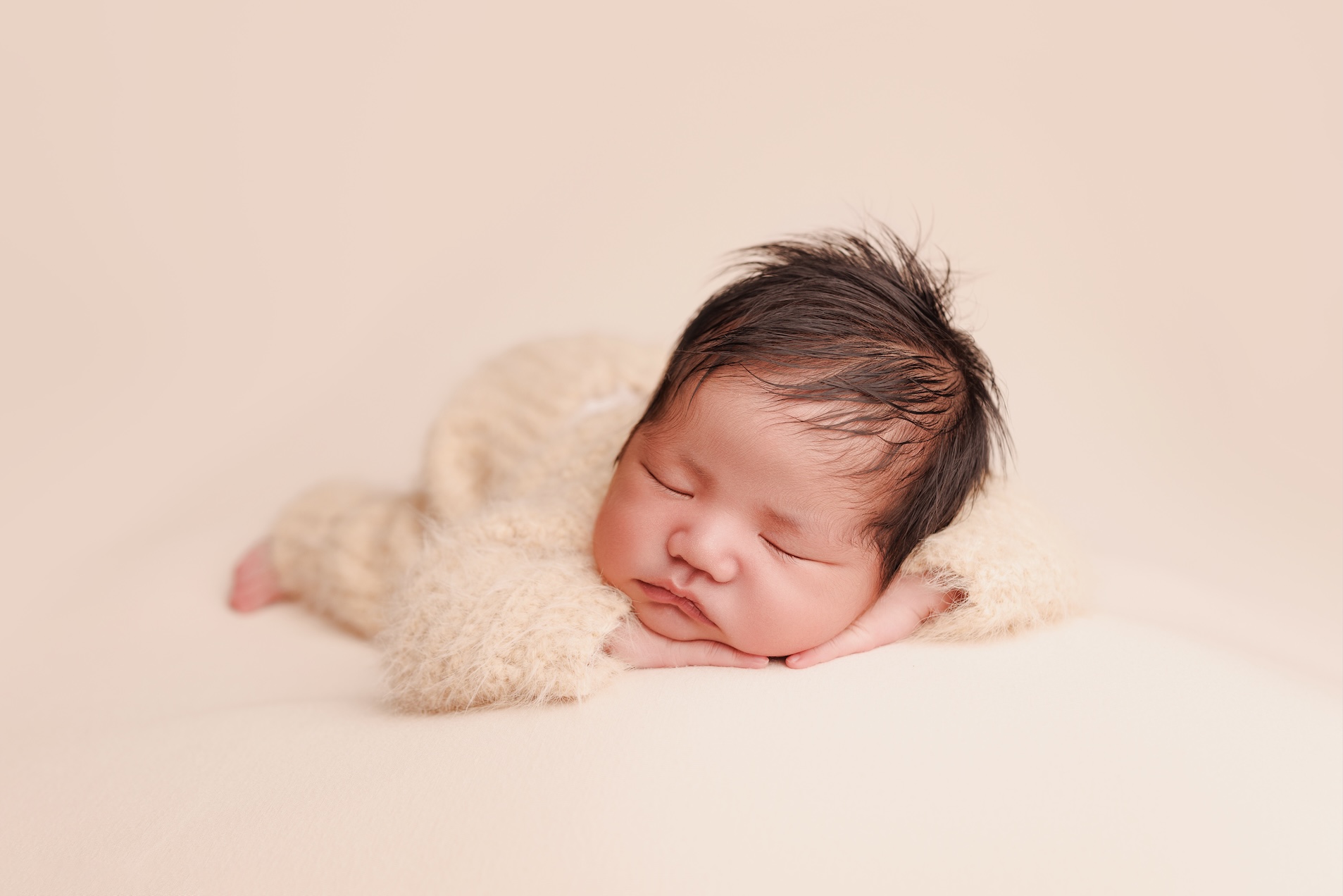Newborn baby in a chin-on-hands pose photographed in an Elk Grove studio.